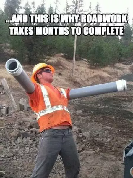 Construction Worker With His Arms Inserted Into Pipes Posing For A Funny Picture Captioned: And This Is Why Roadwork Takes Months To Complete.