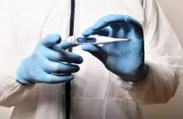 Medical Worker With Surgical Gloves Holding A Thermometer
