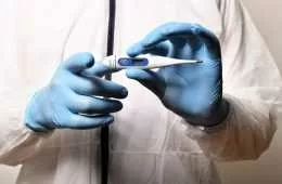 Medical Worker With Surgical Gloves Holding A Thermometer